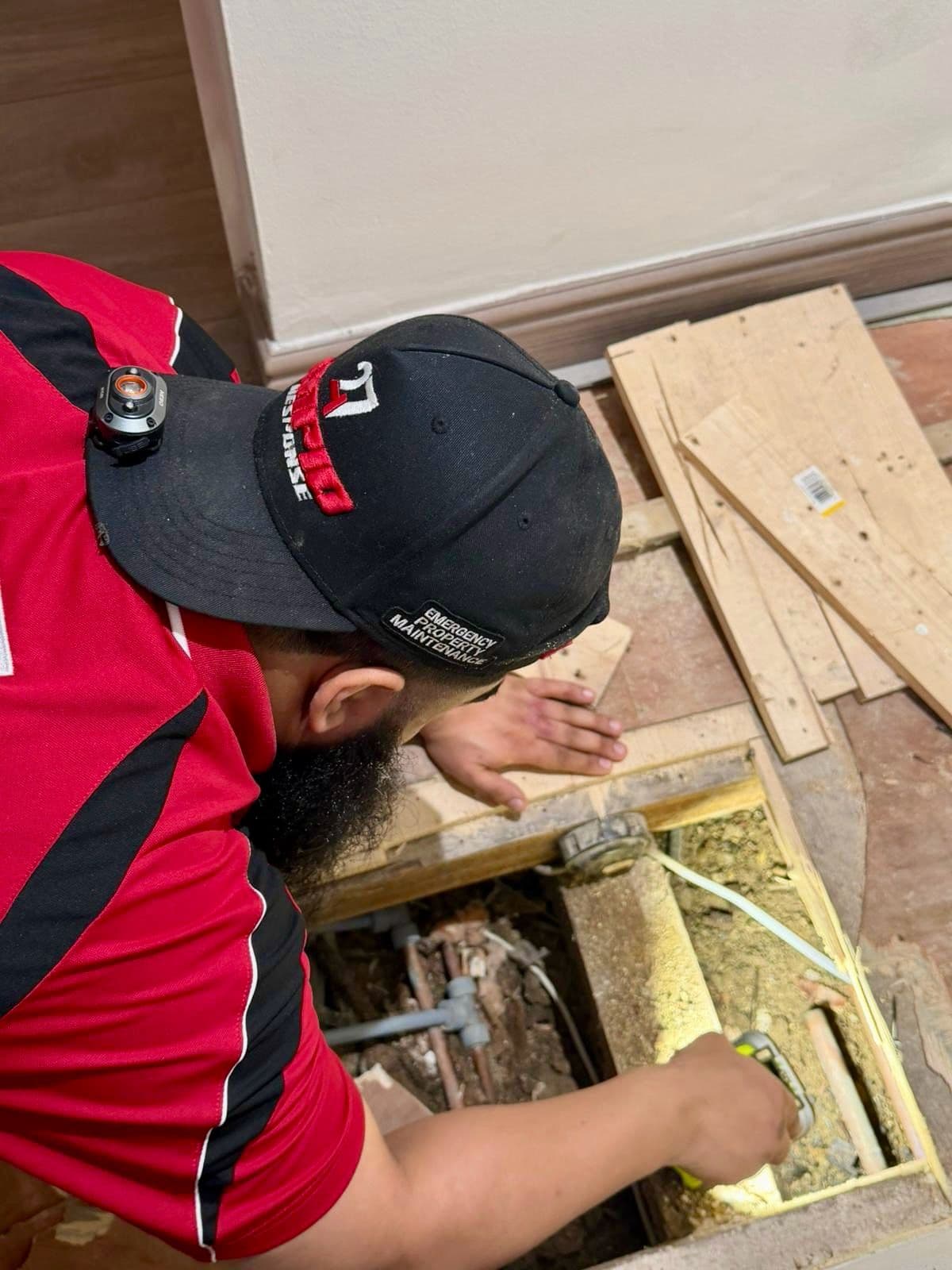 247 Rapid Response engineer using a leak-detection device on pipework under a lifted floor, trace and access in progress