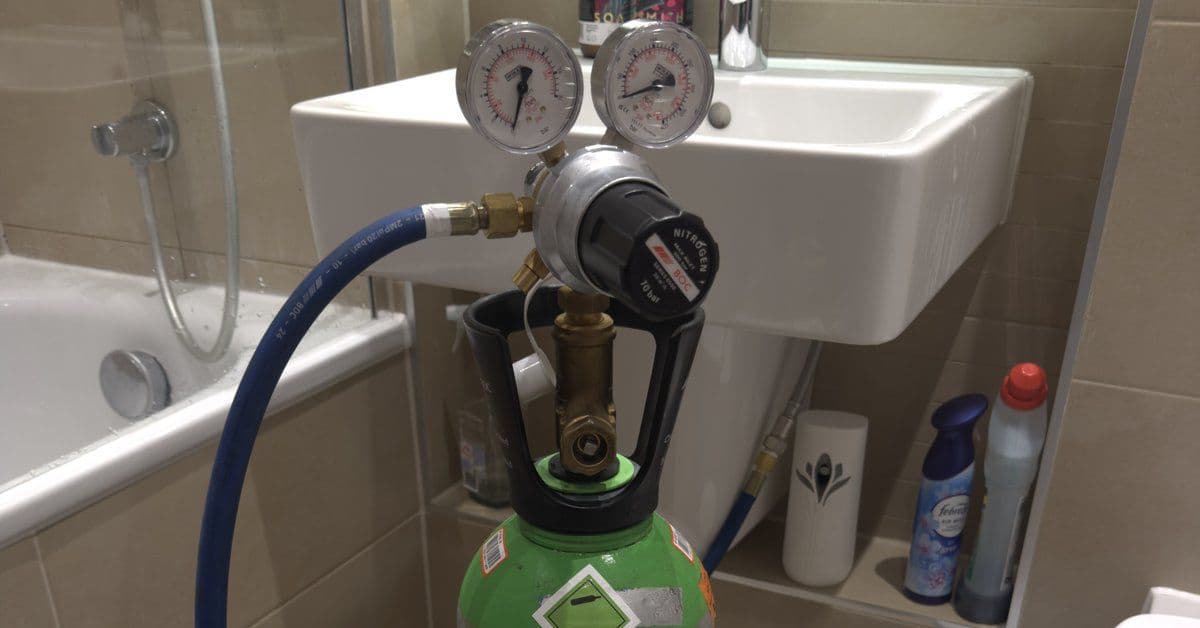 Nitrogen tracer-gas regulator and gauges set up next to a bathroom sink during a 247 Rapid Response leak-detection callout