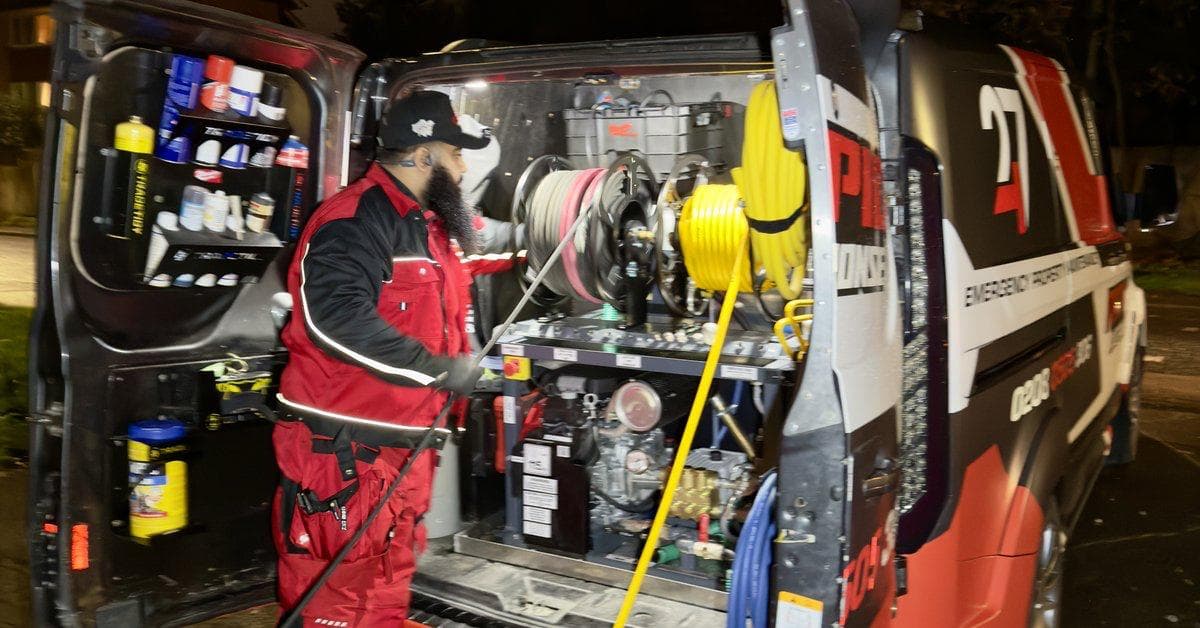 247 Rapid Response engineer at the rear of a fully-kitted emergency response van, high-pressure jetting kit ready, on a London street at night